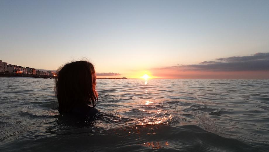 Woman swimming in the sea by Worthing seafront at sunset - credit Zoe Manders