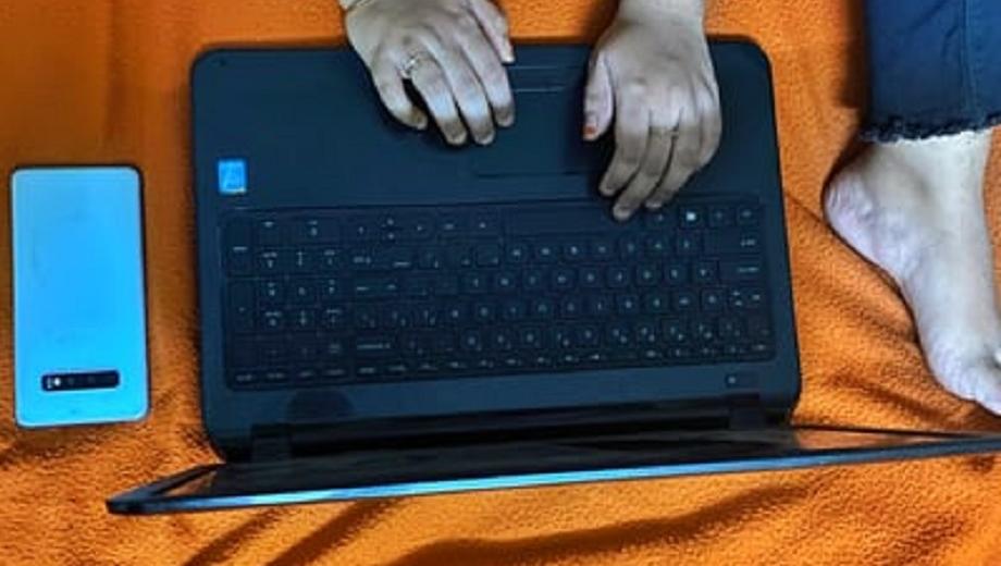 Woman on bed with laptop and phone